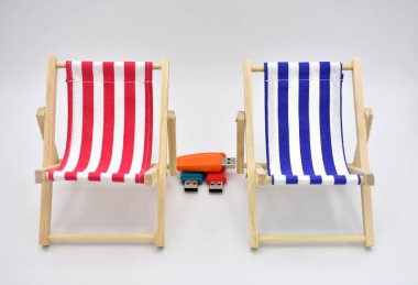 Beyaz arka planda plaj sandalyeleri ve Usb flash bellek sürücüleri.