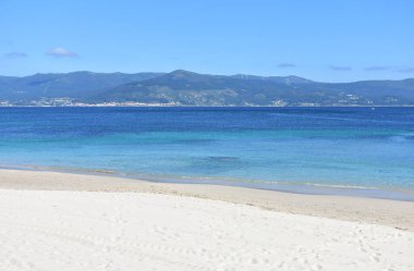 Turkuaz suyu olan körfez, beyaz kum ve mavi gökyüzü olan sahil. San Francisco plajı, Muros, Galiçya, İspanya.