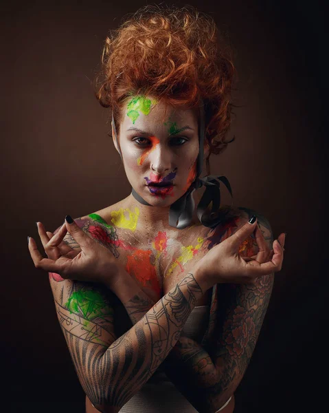 redhead woman with face and body painting on brown background