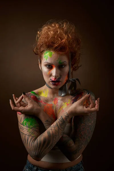 redhead woman with face and body painting on brown background