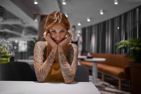 Young tattooed woman sitting in urban city cafe