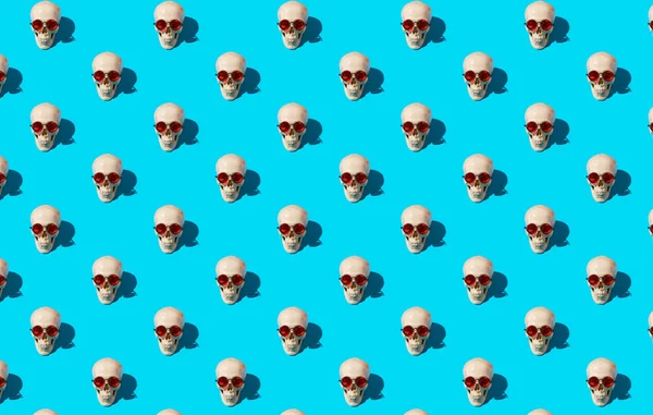 Seamless pattern with human skulls in red glasses on blue background