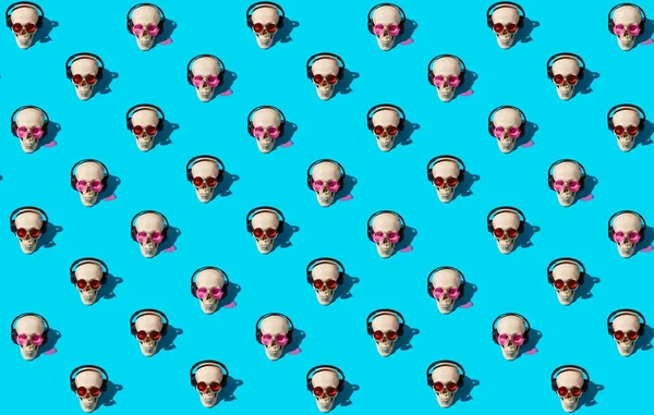 Seamless pattern with human skulls in red and pink glasses and headphones on blue background