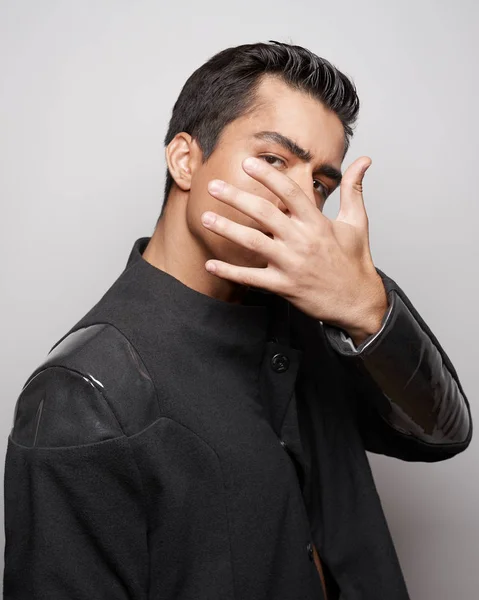 Young stylish man in black outfit posing in grey background