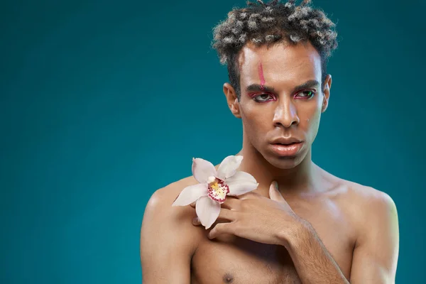 Young african-american male model posing with orchid flower