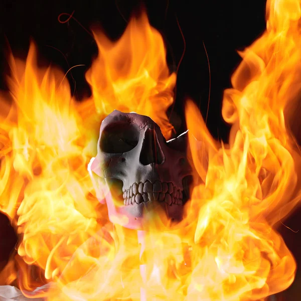 Broken human skull in flame on black background