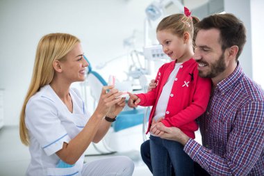 Dişçi kız ve babasının çene dişleri ile gösterir