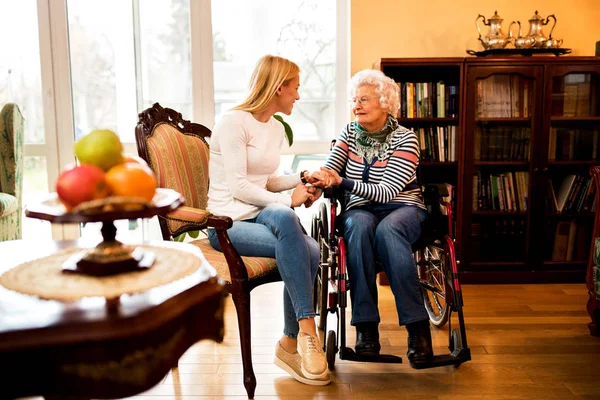 Evde Oturan Nesli Gülümseyen Birlikte Konuşurken Tekerlekli Sandalyede Büyükanne Ziyaret - Stok İmaj