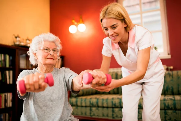 Smilinig Positive Seniorin Genießt Übung Mit Krankenschwester Während Sie Hanteln — Stockfoto