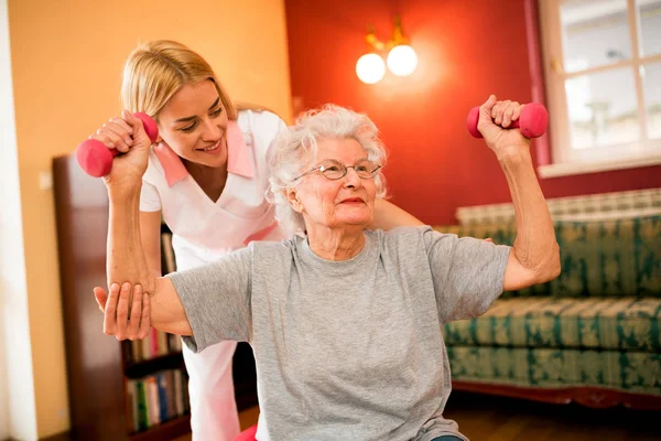 Smilinig Positive Senior Woman Enjoy Exercise Nurse While Holding Dumbbells — Stock Photo, Image