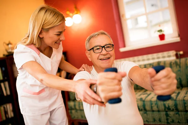 Älterer Mann Macht Übungen Mit Kurzhanteln Während Krankenschwester Ihnen Hilft — Stockfoto