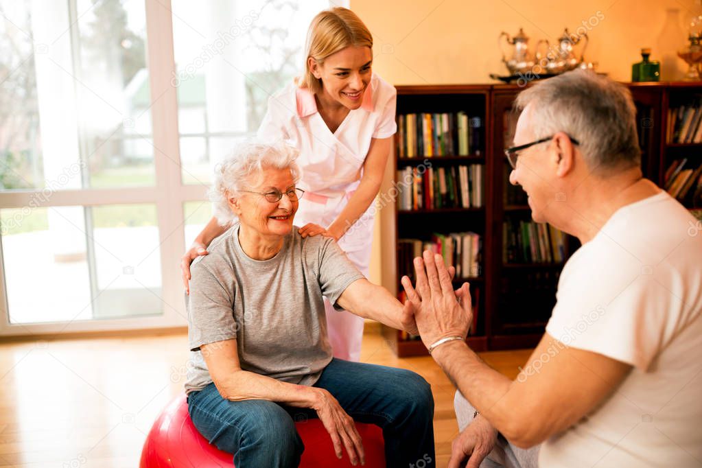 Old mature people doing exercises with nurse at home