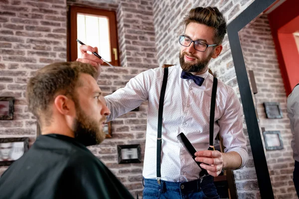 Hairdresser adjusts hair a customer with a comb in barbershop salon