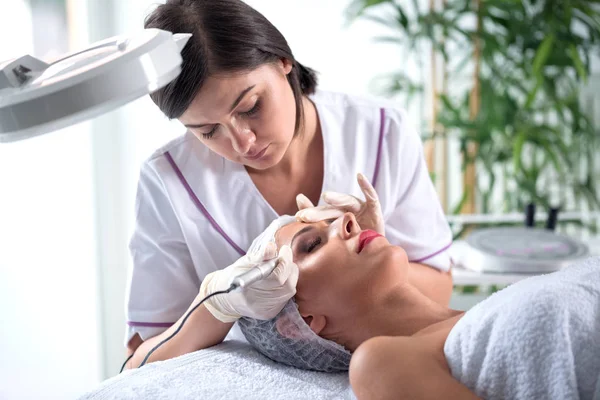 Beautiful woman doing example of permanent makeup treatment at beauty salon