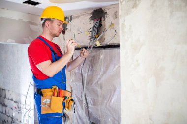 Elektrik iş bir çalışma sitesi içinde yer alan yetenekli bir teknisyeni kontrol altında