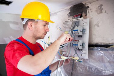 Vasıflı işçi otomatik montaj dağıtım panosu üzerinde kırmızı bir tornavida ile geçer.