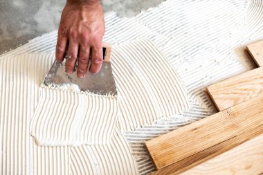 Vasıflı işçi zemin oluşturmak için parke zemin derleme üzerinde çalışıyor