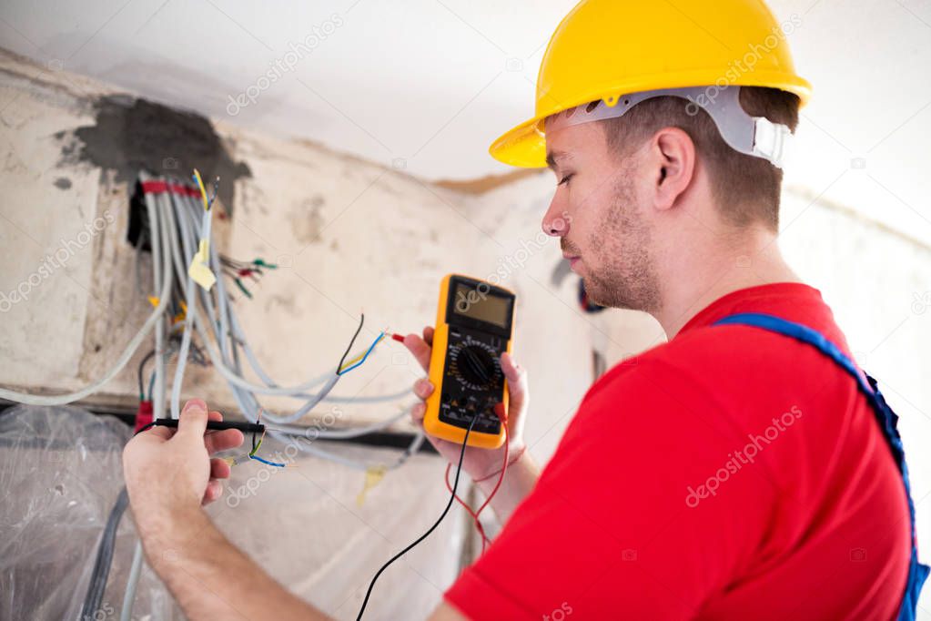 Electrician with unimer testing cable connectivity on a location of distribution board