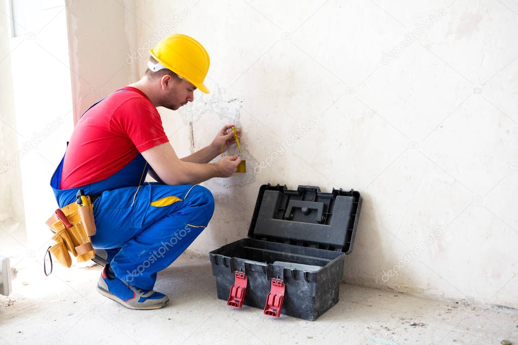 Electrician checking the voltage level in wall socket cables