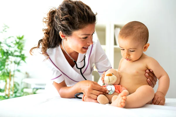 彼女の赤ちゃんの患者に彼のテディベアを調べる方法を示す子供のスペシャ リスト — ストック写真