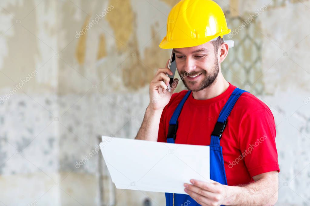 Building engineer arranging technical details via mobile phone insuring everything goes smooth in business 