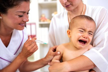 Baby having a theatrical objection to a vaccine shot crying for his mother attention clipart