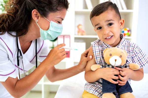 儿童接受疫苗剂量伴随着他的朋友泰迪熊 — 图库照片