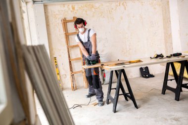 Koruyucu maske takıyor ve bazı ahşap kaplamalar kesme genç işçi 