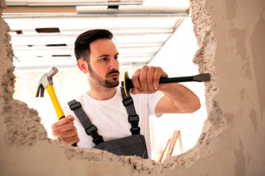 Duvarda bir delik sivri keski ve çekiç ile oyma