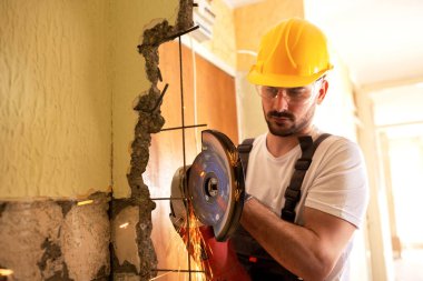 Kurnaz işçi değirmeni kullanarak beton duvar metal parçaları kesme