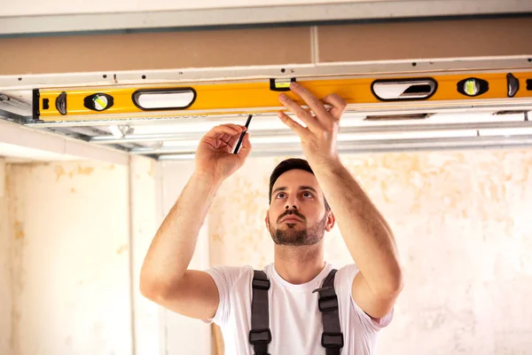 Taking measures with spirit level and marking of the drilling spots on the ceiling