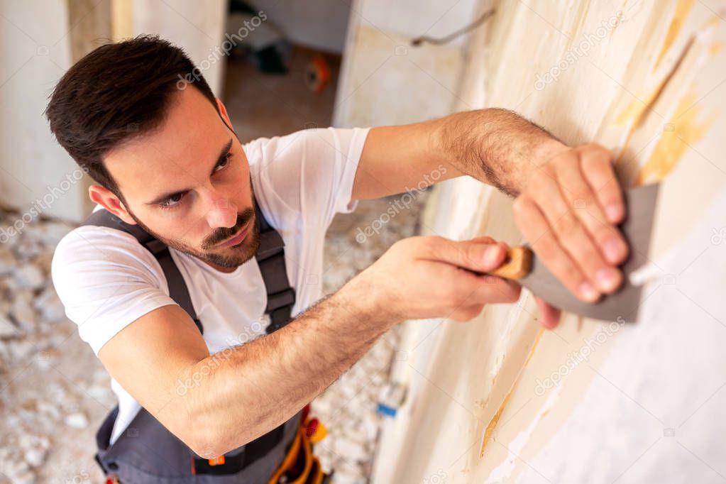 Removing of old wallpaper from the wall with a putty knife