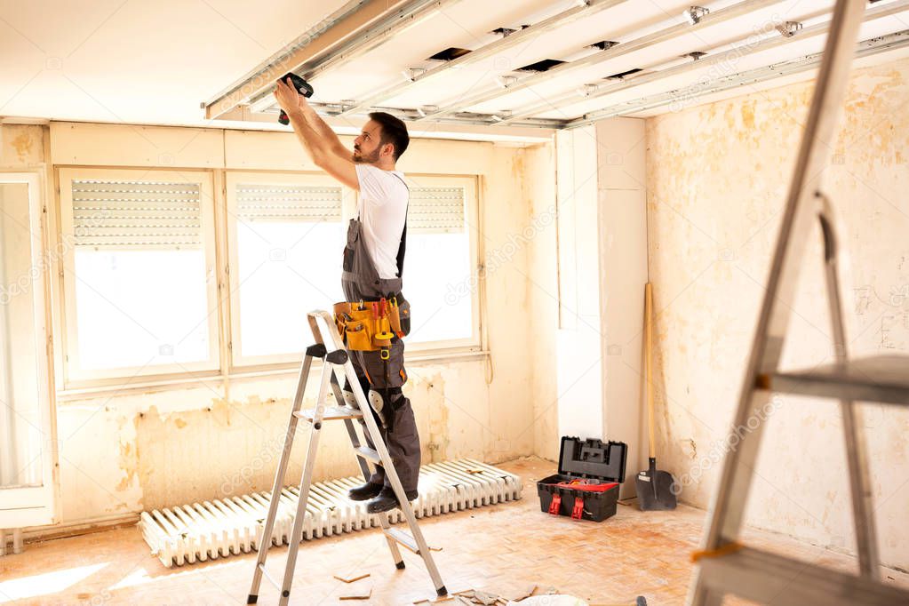 Crafty worker arranging proper order of a ceiling construction using a power tool