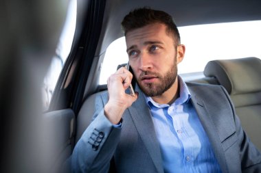 İşadamı otomobilin arka koltuktan gelecekteki projeler hakkında ayrıntılı bilgi düzenleme