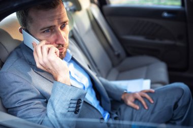 İşadamı otomobilin arka koltuktan gelecekteki projeler hakkında ayrıntılı bilgi düzenleme