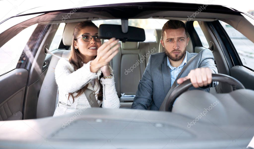 Restless young woman sitting on a  drivers seat looking herself in the mirror