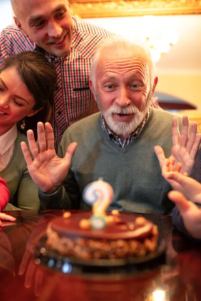 Grandpa making a wish for his birthday and blowing of a candle