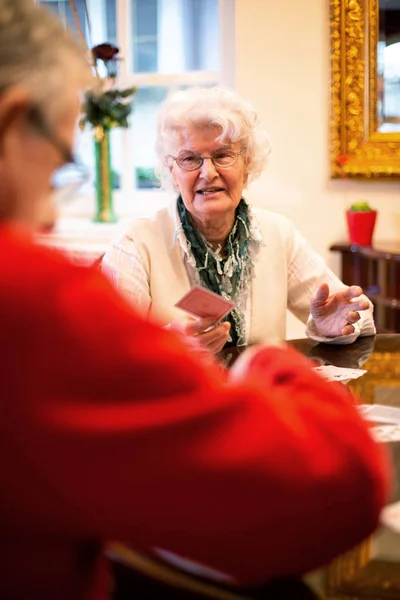 Two elder people playing cards and having a good time in a retirement home