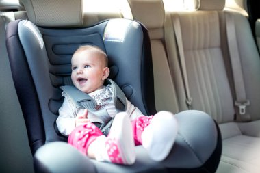 Gülen ve having fun bebek araba koltuğuna olurken güzel bebek