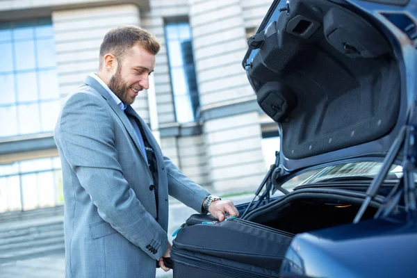 Homme classe plaçant les bagages dans le coffre de la voiture — Photo