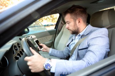 Dikkatsiz adam sürüş sırasında cep telefonunu kontrol
