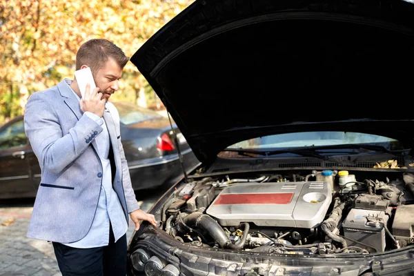 Atractivo joven molesto hombre haciendo una llamada mientras su coche se rompió dow — Foto de Stock