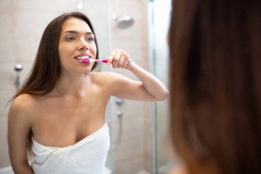 Ayna önünde duran kız ve diş fırçalama