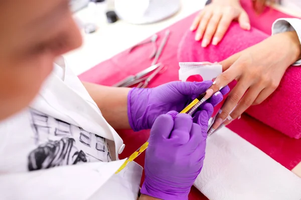 Artificial nail enhancement being applied by the hands of an exp