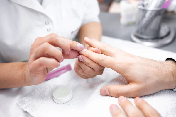 Aseo de uñas en las manos del hombre durante el tratamiento de manicura —  Fotos de Stock