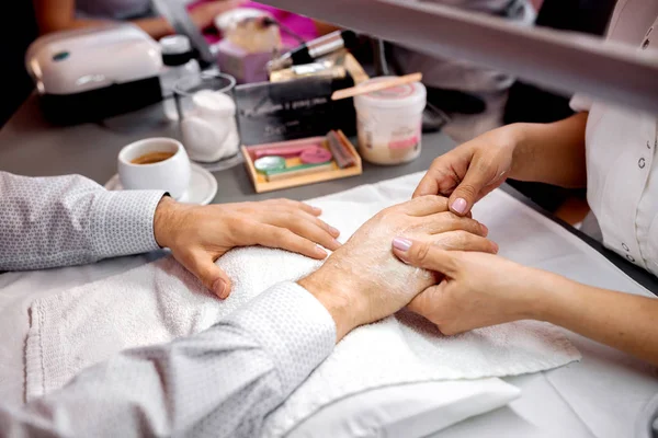 Manicura sosteniendo una mano de un hombre para un tratamiento posterior — Foto de Stock