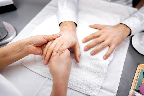 Manicurist innehar en hand av en man för vidare behandling — Stockfoto