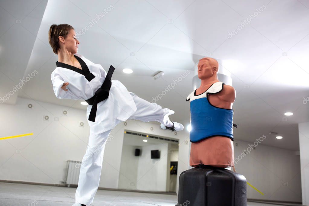 Young woman with physical disability performing kicks on a punch