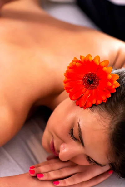 Menina encantadora com flor no cabelo tendo uma massagem — Fotografia de Stock