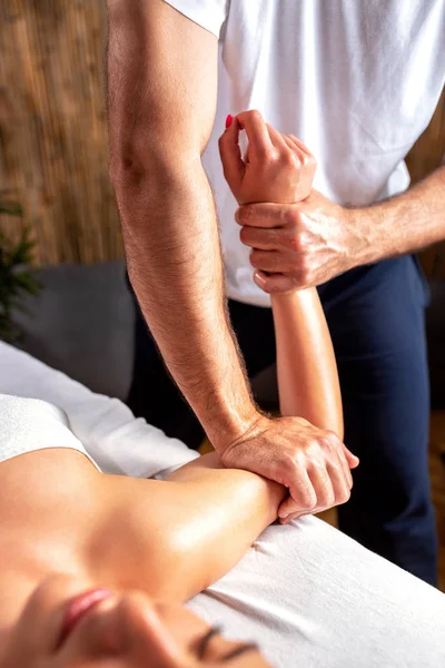 Starke Arme des Masseurs, der sanfte Arme seines Klienten massiert — Stockfoto